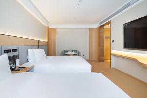 ein Hotelzimmer mit zwei Betten und einem Flachbildfernseher in der Unterkunft JI Hotel Shanghai Caohejing Hongcao Road in Shanghai
