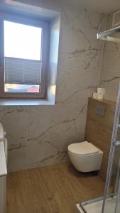 une salle de bain avec des toilettes blanches et une fenêtre dans l'établissement Apartament Floriana, à Radom
