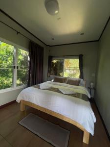 a bedroom with a large bed and a window at Rai Boonsom in Phrao