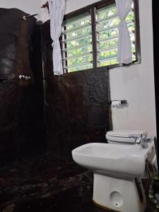 a bathroom with a white toilet and a window at Mimi ni wako in Watamu