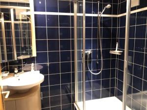 ハスリベルクにあるHaus Polluxの青いタイル張りのバスルーム(シャワー、シンク付)