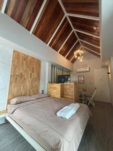 ein großes Bett in einem Zimmer mit Holzdecken in der Unterkunft Dehut Boutique Homestay hut2 in Khon Kaen