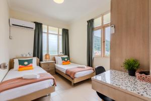 a bedroom with two beds and a desk and windows at EE's Summer House - Homestay 3 min walk to beach in Batu Ferringhi +71 photos