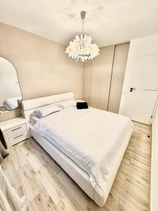 ein Schlafzimmer mit einem großen weißen Bett und einem Kronleuchter in der Unterkunft FLH - Obralix Home in Sibiu