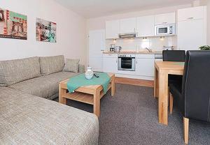 uma sala de estar com um sofá e uma mesa e uma cozinha em Ferienwohnungen Alter Sielweg Wohnung 10 em Bensersiel