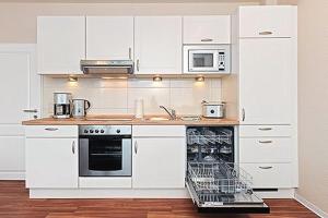 uma cozinha com armários brancos, um fogão e micro-ondas em Ferienwohnungen Alter Sielweg Wohnung 10 em Bensersiel