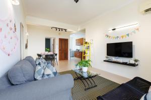 a living room with a blue couch and a tv at EE's Summer House - Homestay 3 min walk to beach in Batu Ferringhi