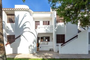 a white house with a palm tree in front of it at Apto Familiar frente a cala in Cala en Forcat