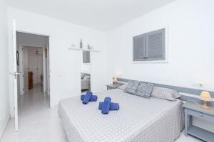 a white bedroom with a bed with blue pillows on it at Apto Familiar frente a cala in Cala en Forcat +16 photos