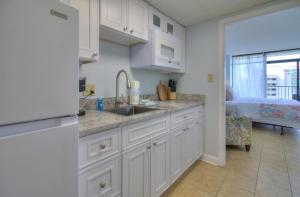 een keuken met witte kasten, een wastafel en een bed bij Verandas - 808 in Myrtle Beach