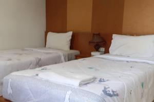 two beds in a room with white sheets and pillows at Praew Mansion in Kamala Beach