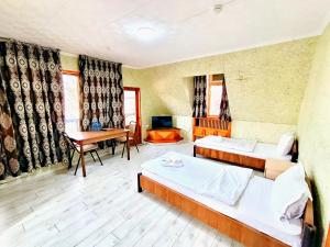 a room with two beds and a desk and a table at The green regency in Toshkent-Passajir Bekati