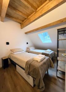zwei Betten in einem Zimmer mit Holzdecken in der Unterkunft Le Vieux Bourg Apartment 4, Spacious 3 bedroom Apartment, Ski & Cycle in Le Bourg-dʼOisans