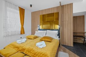 a bedroom with a yellow bed with two towels on it at Apartmani Point Pregrada in Pregrada