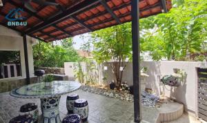 a patio with a glass table and a pergola at Landed Spacious House at Cangkat Delima Gelugor Penang in Gelugor