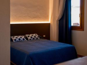 a bedroom with a blue bed with two pillows at Vie D'Alt Wine and Rooms in Prepotto