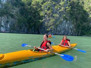 two girls kayaking in a yellow raft in the water at CATBA PANDORA Hotel & Travel in Cat Ba