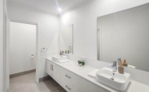 a white bathroom with two sinks and a large mirror at Kincaid Travellers Townhouse - Central Wagga in Wagga Wagga +24 photos