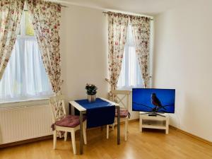 een woonkamer met een tafel en een tv bij Villa Fortuna Gästehaus App Hiddensee in Ahlbeck