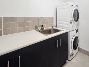 a kitchen with a sink and a washing machine at Kincaid Travellers Townhouse - Central Wagga in Wagga Wagga