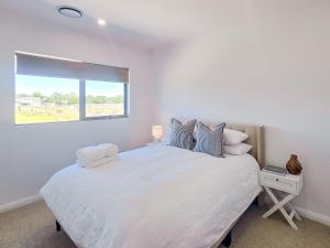 a white bedroom with a large bed with a window at Kincaid Travellers Townhouse - Central Wagga in Wagga Wagga