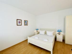 een slaapkamer met een wit bed en 2 lampen bij Villa Fortuna Gästehaus App Hiddensee in Ahlbeck