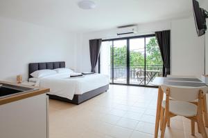 a bedroom with a bed and a kitchen with a balcony at Stay White Orchid in Krabi