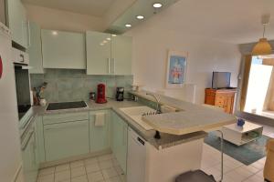 una cucina con mobili bianchi e un piano di lavoro di Lagune Azur – Séjour cosy vue mer avec Wi-Fi a Sète Altre 4 foto