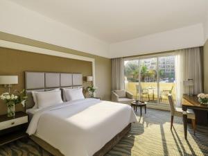 a hotel room with a large bed and a desk at Rixos Bab Al Bahr - Ultra All Inclusive in Ras al Khaimah