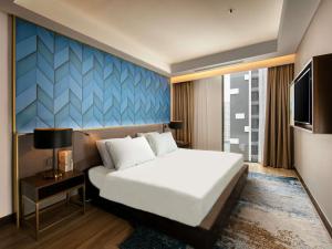 a hotel room with a bed and a tv at Mövenpick Living West Hanoi in Hanoi