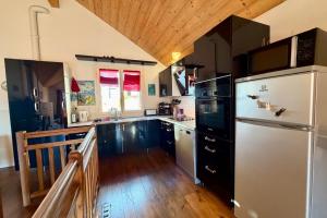 Il comprend une cuisine équipée d'un réfrigérateur blanc et du parquet. dans l'établissement Charming and bright cottage in Briançon, à Briançon