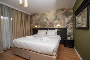 ein Schlafzimmer mit einem großen weißen Bett und einem Gemälde in der Unterkunft Private garden room by MANAGR in Timisu de Jos