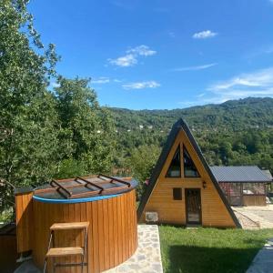 a small wooden house with a stool in front of it at Carpatina Runcu căsuțe tip A in Runcu