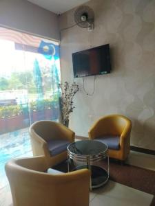 a living room with two chairs and a table and a tv at Get Inn Hotel in Gua Sai +4 photos
