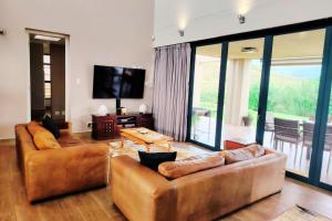 a living room with two brown couches and a television at Dierama Dream, Cathkin Estates - 4 adults and 2 children, 12 years or younger in Ardmore