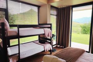 a bedroom with two bunk beds in front of a window at Dierama Dream, Cathkin Estates - 4 adults and 2 children, 12 years or younger in Ardmore
