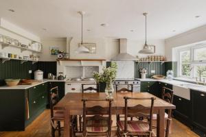 Una cocina con una mesa de madera y armarios verdes. en Old school house surrounded by countryside, en Earls Colne
