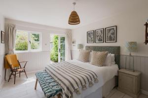 Un dormitorio con una cama y una silla y ventanas. en Old school house surrounded by countryside, en Earls Colne