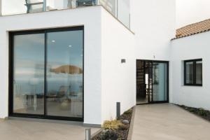 a white house with large sliding glass doors at Finca el Moral by Huskalia in Los Llanos de Aridane