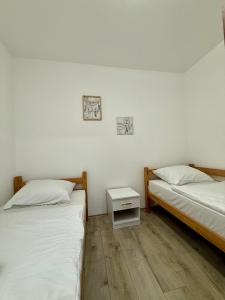 two beds in a room with white walls and wooden floors at Ski kuca Elbrus in Jahorina