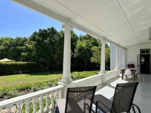 a white porch with chairs and tables on it at Le Manse in Franschhoek