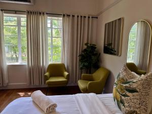 a bedroom with two chairs and a bed and windows at Le Manse in Franschhoek