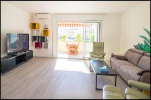 a living room with a couch and a tv at L'ariot 1984 - appartement cosy avec terrasse, parking et wifi in Sète +12 photos