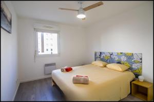 a bedroom with a large bed with a yellow blanket at L'ariot 1984 - appartement cosy avec terrasse, parking et wifi in Sète