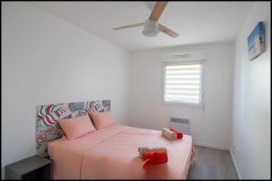 a bedroom with a bed with pink sheets and a window at L'ariot 1984 - appartement cosy avec terrasse, parking et wifi in Sète