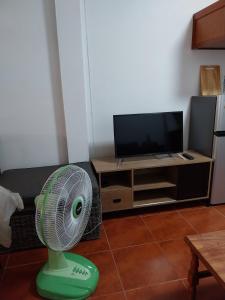 a green fan in a living room with a tv at House in the heart of Kamala in Kamala Beach