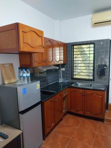 a kitchen with wooden cabinets and a white refrigerator at House in the heart of Kamala in Kamala Beach