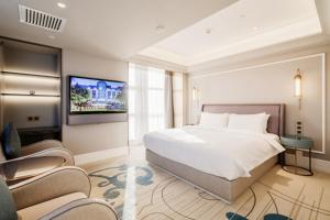 a bedroom with a large bed and a flat screen tv at Mercure Hohhot Downtown in Hohhot