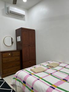 a bedroom with a bed and a dresser and a mirror at Magnolia 3 Homestay in Kampung Raja +6 photos