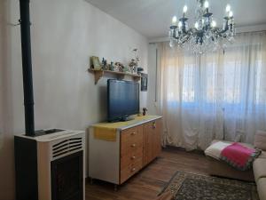 a living room with a television on a dresser with a chandelier at Casa Aurora Nicole in Pergine Valsugana